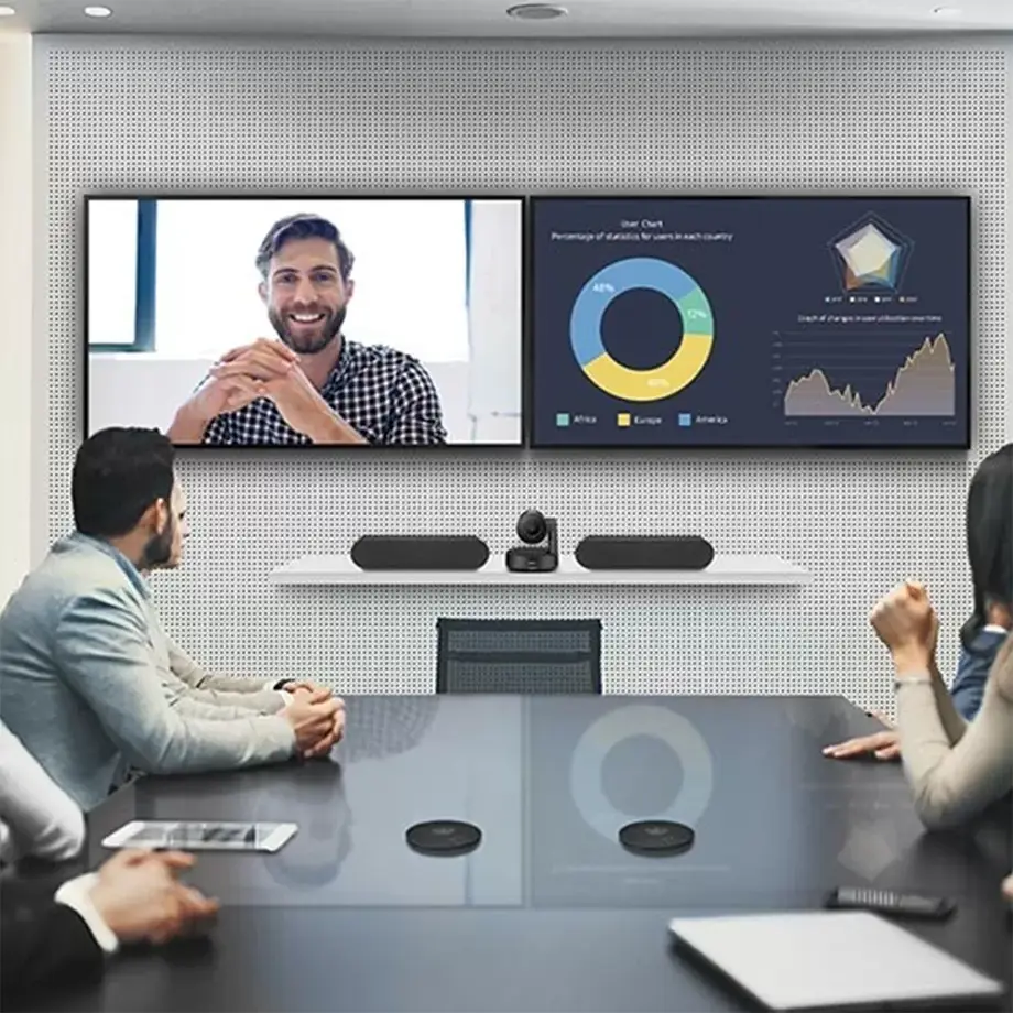 Modern video conferencing room with dual displays, Logitech camera and speakers, showcasing AV integration setup for hybrid meetings